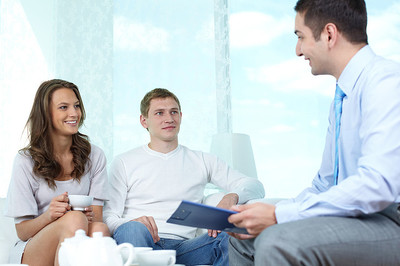 微笑的年轻夫妇与保险经纪人或投资顾问握手三人在办公室开会达成协议